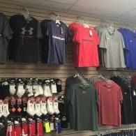 Store display of athletic shirts in black, red, gray, and blue on wall racks, with socks below