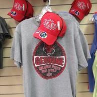 Gray T-shirt with red logo, displayed on a wall with red baseball caps above it