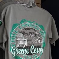 Gray T-shirt with a green circular graphic reading “Greene County,” hanging on a rack
