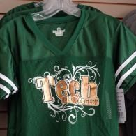 Green “Tech” jersey with white sleeve stripes and ornate design on the front, hanging on a rack