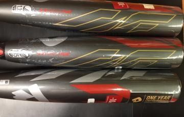 Three black and red baseball bats stacked horizontally on a shelf, with gold graphics and “ONE YEAR” text.