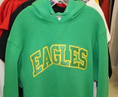 Green hoodie with yellow “EAGLES” text hanging on a clothing rack