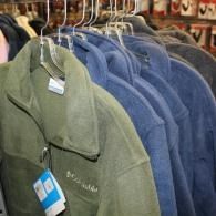 Green and blue fleece jackets on hangers in a clothing store