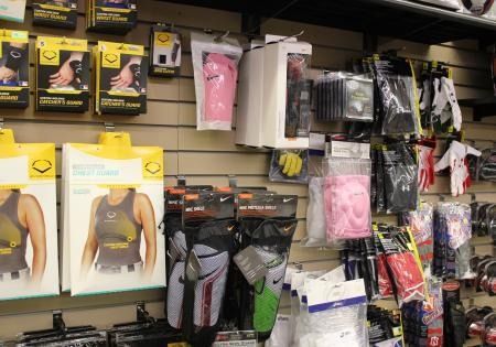 Store display of assorted sport gear and safety pads in plastic packaging on a wall rack.