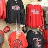 Red and black graphic long-sleeve shirts hanging on display in a sports merchandise store.