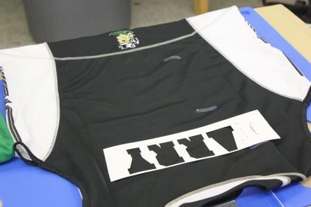 Black-and-white sports jersey laid on a blue surface, with a white number panel on the front.