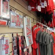Arkansas State University fan merchandise displayed on store shelves, with red and gray shirts and signs.