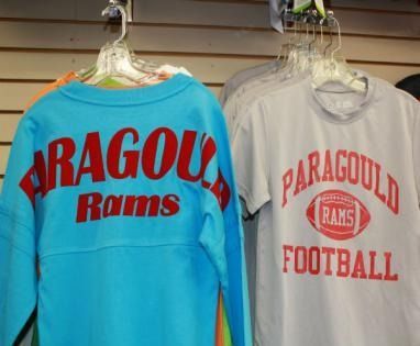 Two Rams sweatshirts hanging on racks, one turquoise and one white, both with red PARAGOULD lettering.