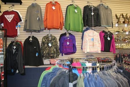 Clothing store display with hanging hoodies and jackets in red, gray, orange, green, purple, and pink.