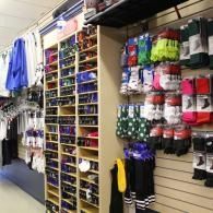 Sporting goods store aisle with hanging socks, gloves, and shelves of small accessories.