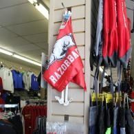 Red Razorback flag hanging in a sports store aisle beside rows of red and black apparel