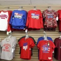 T-shirts hanging on a store display wall, in red, blue, white, gray, and camouflage patterns