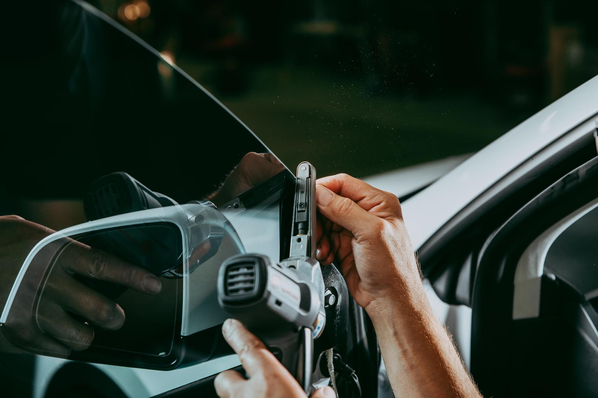 A person is polishing a blue car with a cloth.