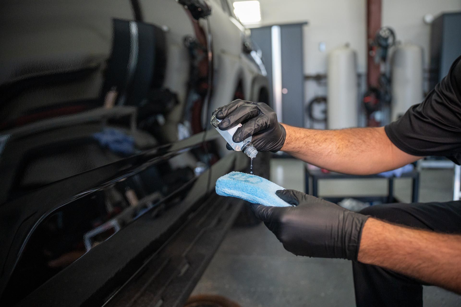 A person is polishing a blue car with a cloth.