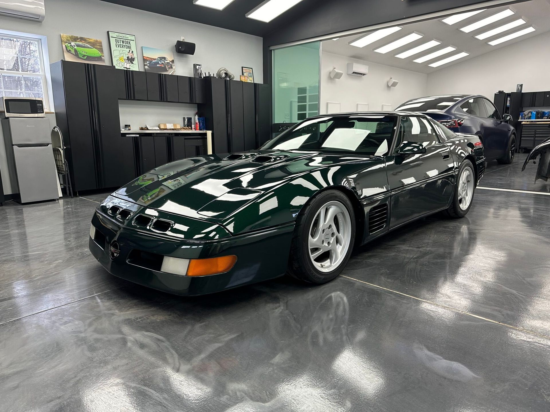 A green corvette is parked in a garage.