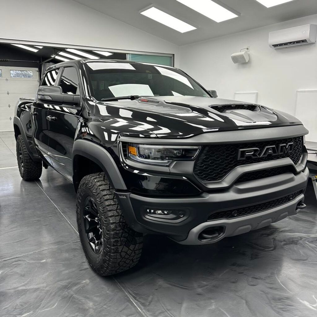 A black ram 1500 raptor is parked in a garage.