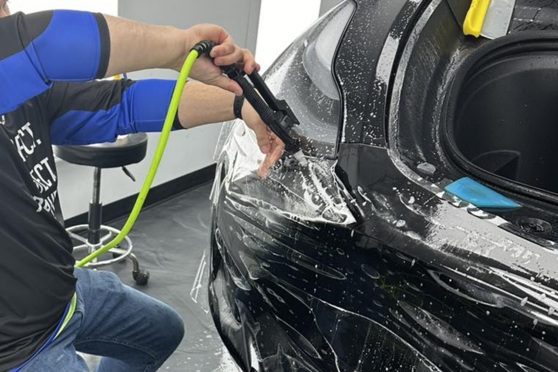 A man is spraying a car with a hose.