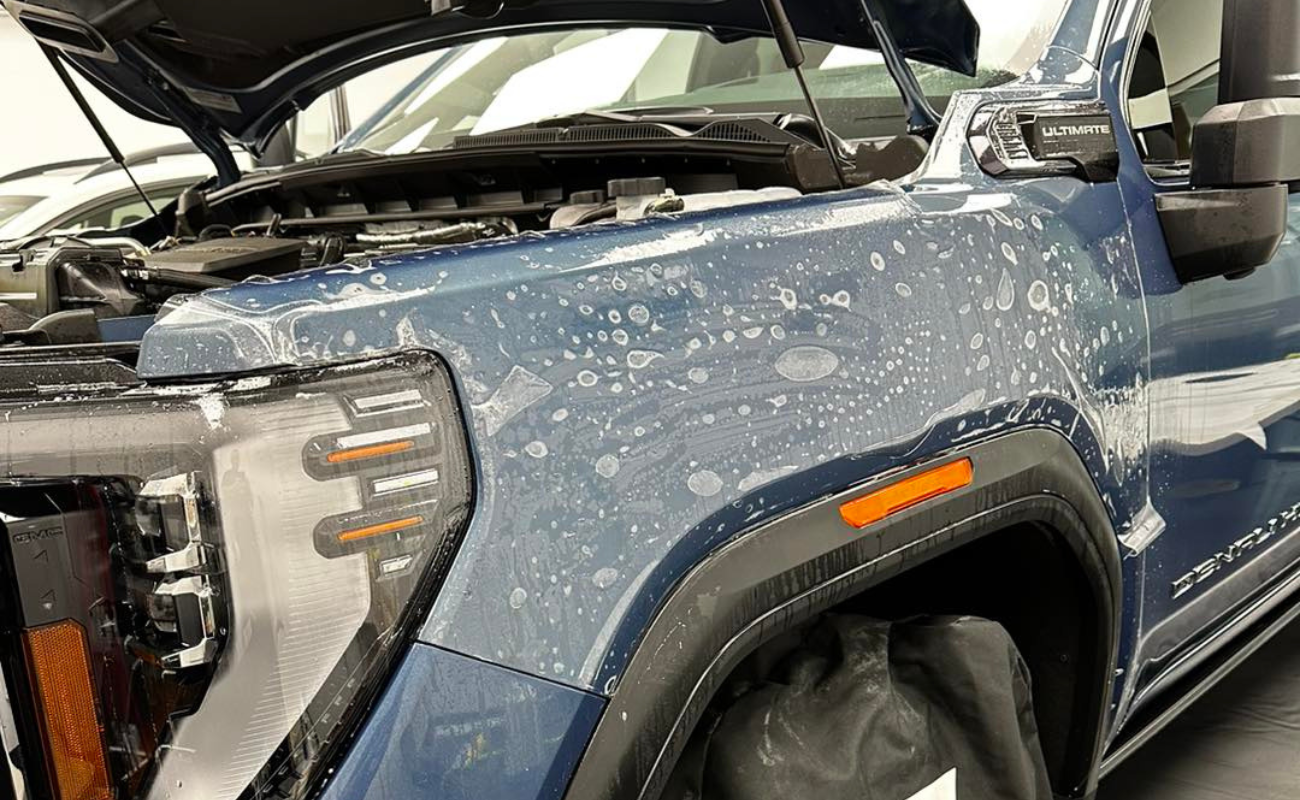 A close up of a blue truck with the hood up.