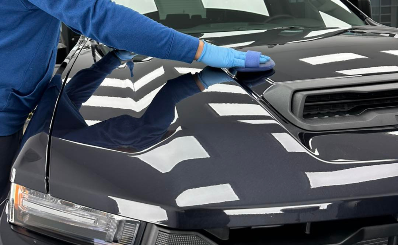 A person is polishing the hood of a black car.