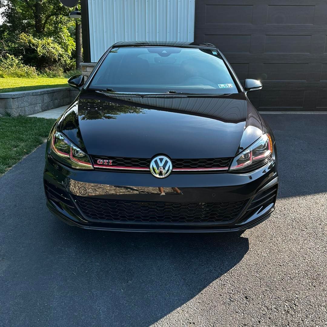 A black volkswagen golf is parked in a driveway.