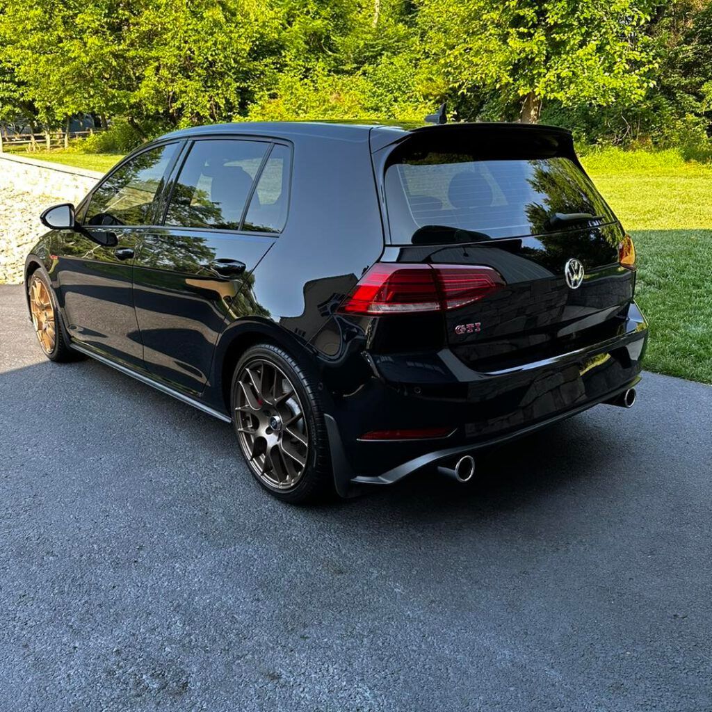A black volkswagen golf is parked in a driveway.