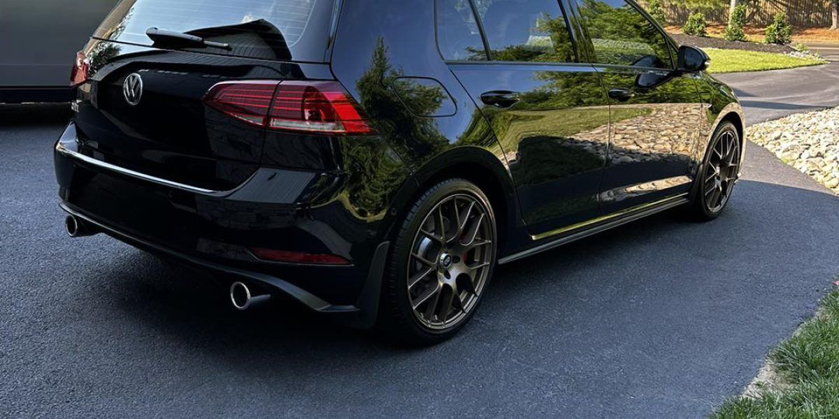 A black volkswagen golf is parked in a driveway.