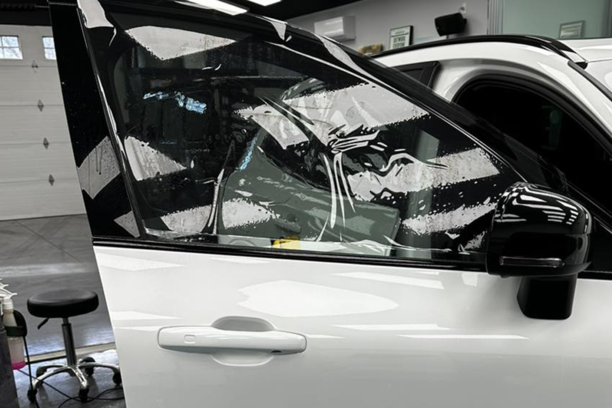 A white car is sitting in a garage with its door open.