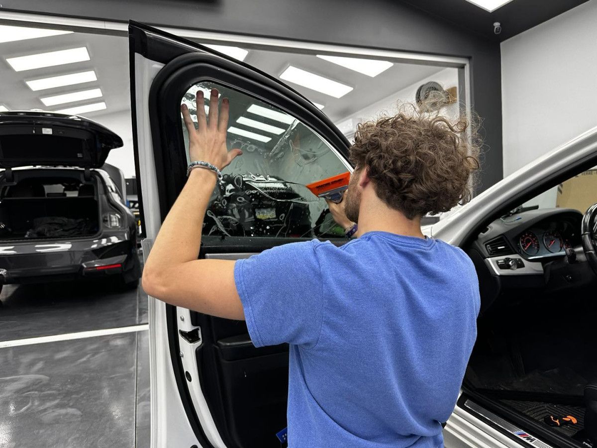 A man is applying window tinting to a car door.