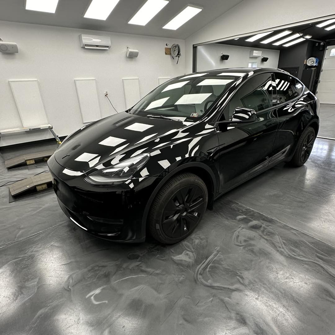 A black tesla model y is parked in a garage.
