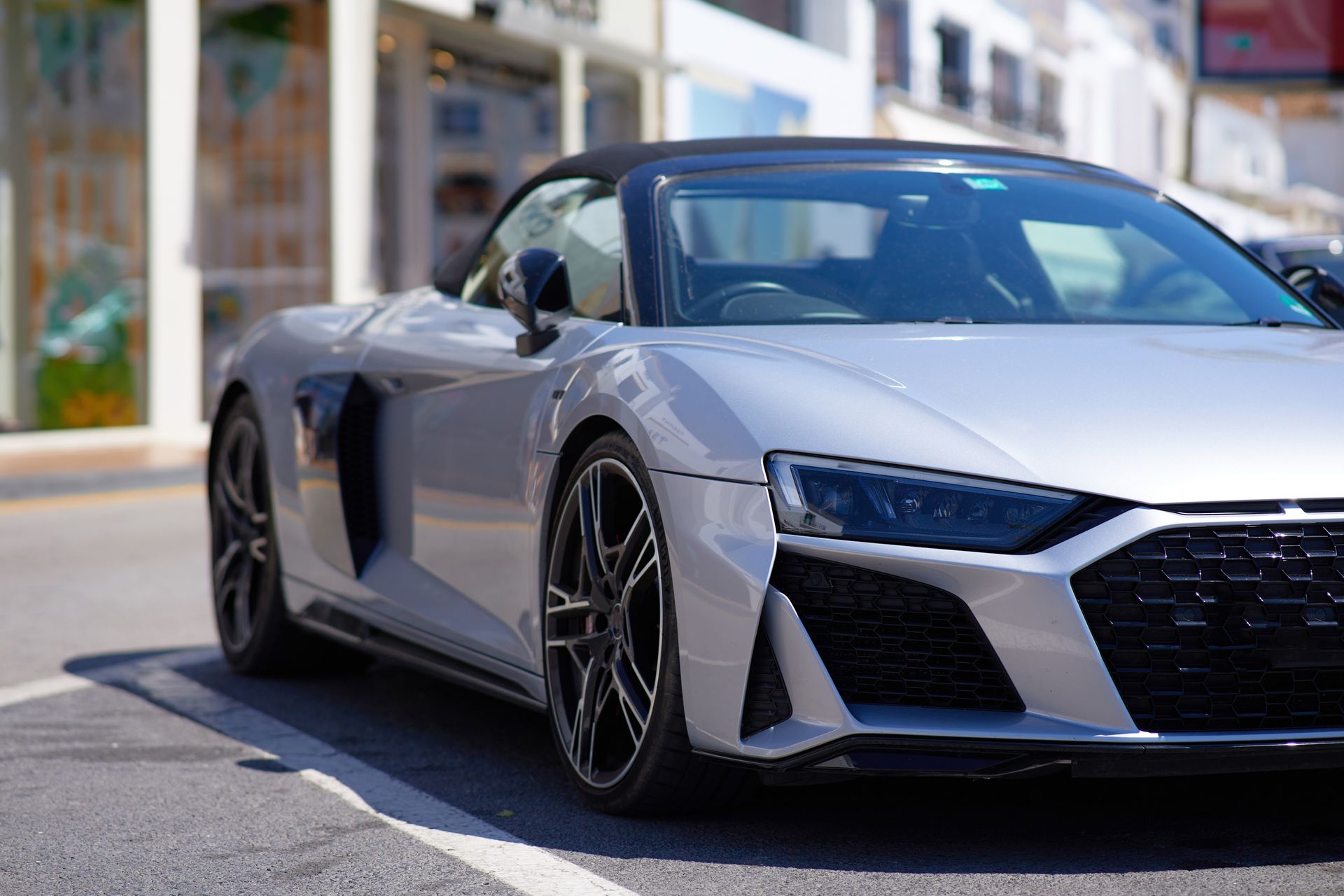 A silver sports car is parked on the side of the road.