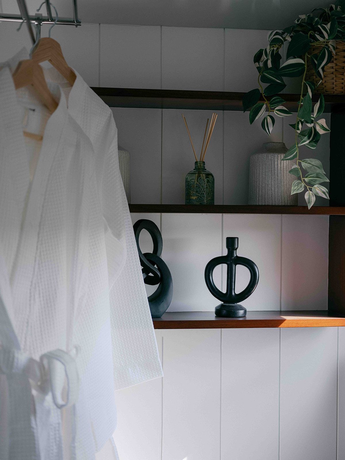 White robe hanging in a closet with shelves, decor, and a potted plant
