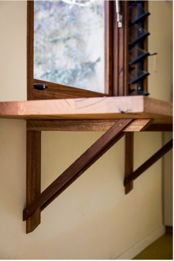 A wooden shelf is attached to a wall next to a window — Matt Loder Constructions in Bulli, NSW