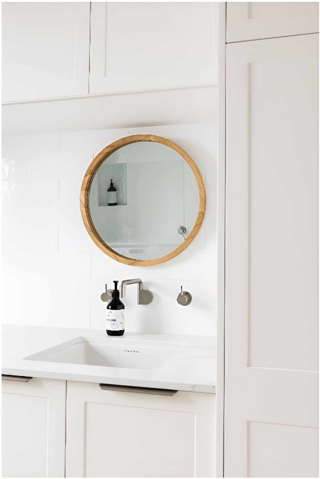 A Bathroom Sink With a Round Mirror Above It — Matt Loder Constructions in Bulli, NSW
