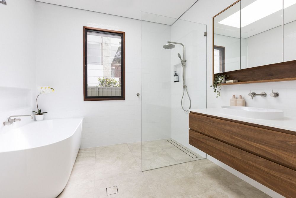 A Bathroom With A Bathtub, Sink, Mirror And Walk In Shower — Matt Loder Constructions in Bulli, NSW