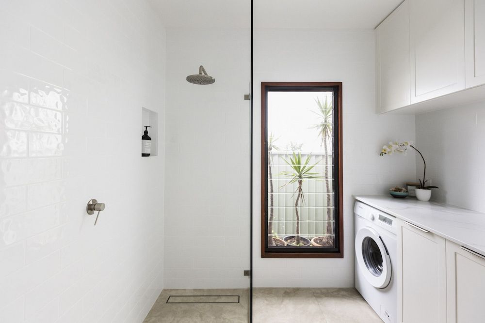 A Laundry Room With A Washer And Dryer, A Shower, And A Window — Matt Loder Constructions in Thirroul, NSW