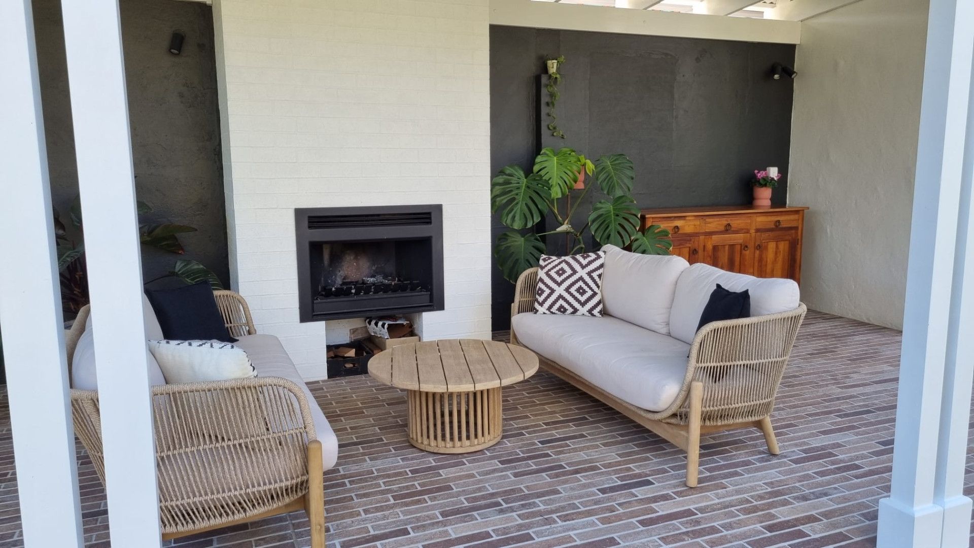 A patio with a couch , chairs , table and fireplace. — Matt Loder Constructions in Bulli, NSW