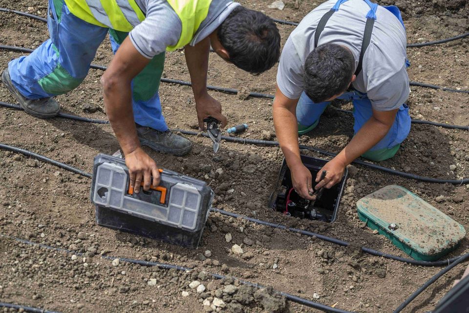 two men are working on a irrigation system in the dirt
