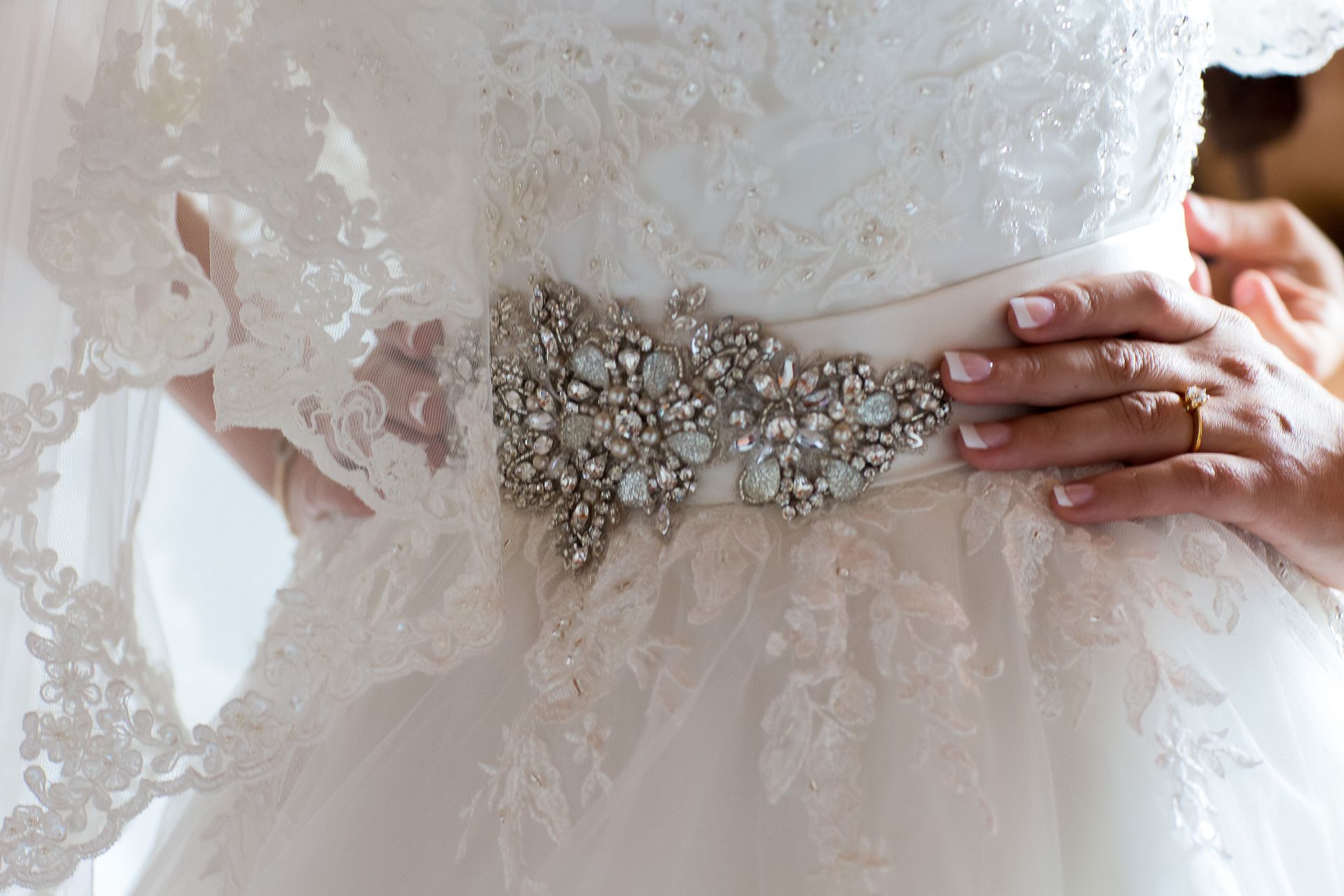 weißes Hochzeitskleid mit Perlen verziert. Kleid ist angezogen mit Silver Gürtel und Schleier.