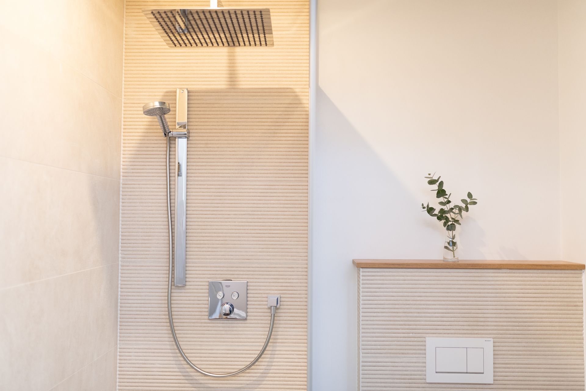 offenes Badezimmer mit Naturstein verfliest und Regendusche. warme Beleuchtung, modern eingerichtet.
