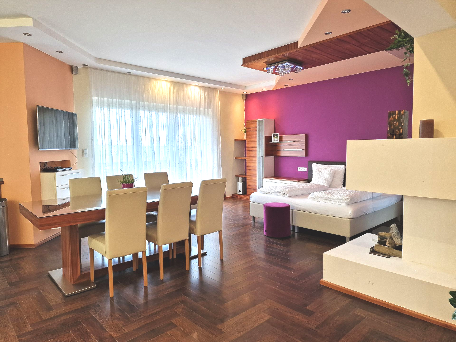 Große Garden Suite mit Kamin und Doppelbett. Die Wandfarbe ist Magenta hinter dem Bett. Hunde sind willkommen.