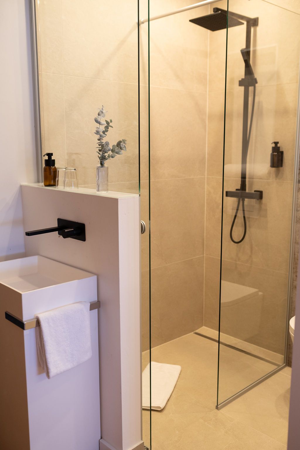 offenes Badezimmer mit Naturstein verfliest und Regendusche. warme Beleuchtung, modern eingerichtet.