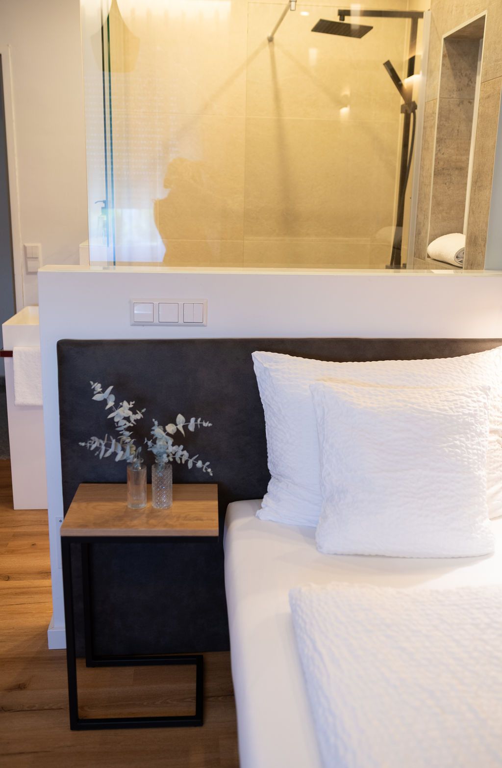 offenes Badezimmer mit Naturstein verfliest und Regendusche. warme Beleuchtung, modern eingerichtet.