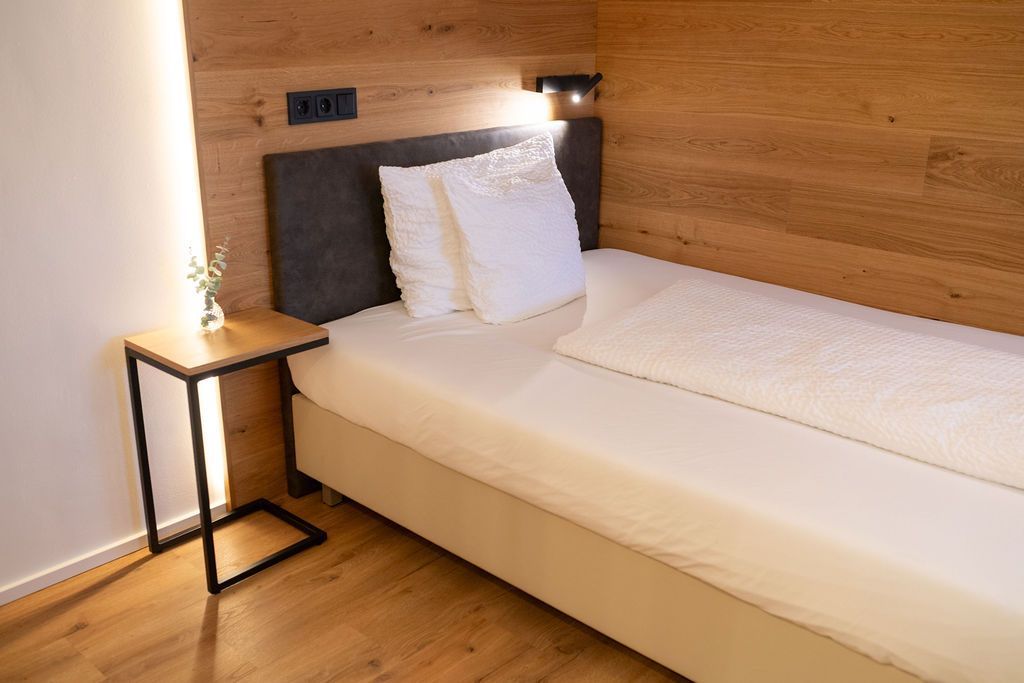 Eiche Queensize. Bett an holzverkleideten Wand. Warme Beleuchtung