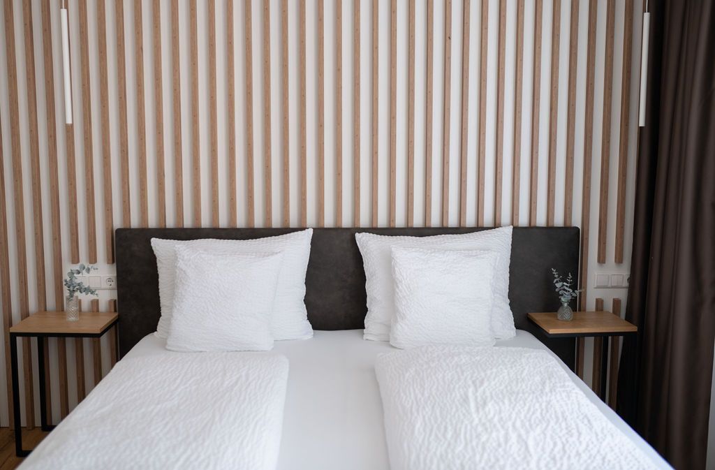 Garten Zimmer. Großes Doppelbett. Die Wand hinter dem Bett ist mit Eiche-Holzpanelen verkleidet. Viel natürliches Licht.