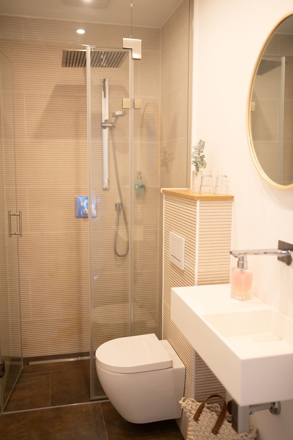 offenes Badezimmer mit Naturstein verfliest und Regendusche. warme Beleuchtung, modern eingerichtet.