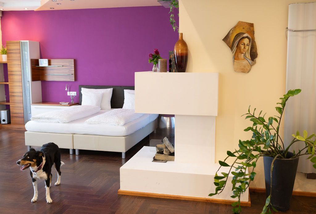 Große Garden Suite mit Kamin und Doppelbett. Die Wandfarbe ist Magenta hinter dem Bett. Hunde sind willkommen.