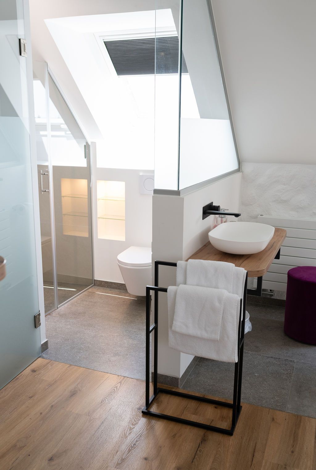 Rooftop Suite mit großem Doppelbett. Freistehende Badewanne neben dem Bett und offenes Badezimmer.