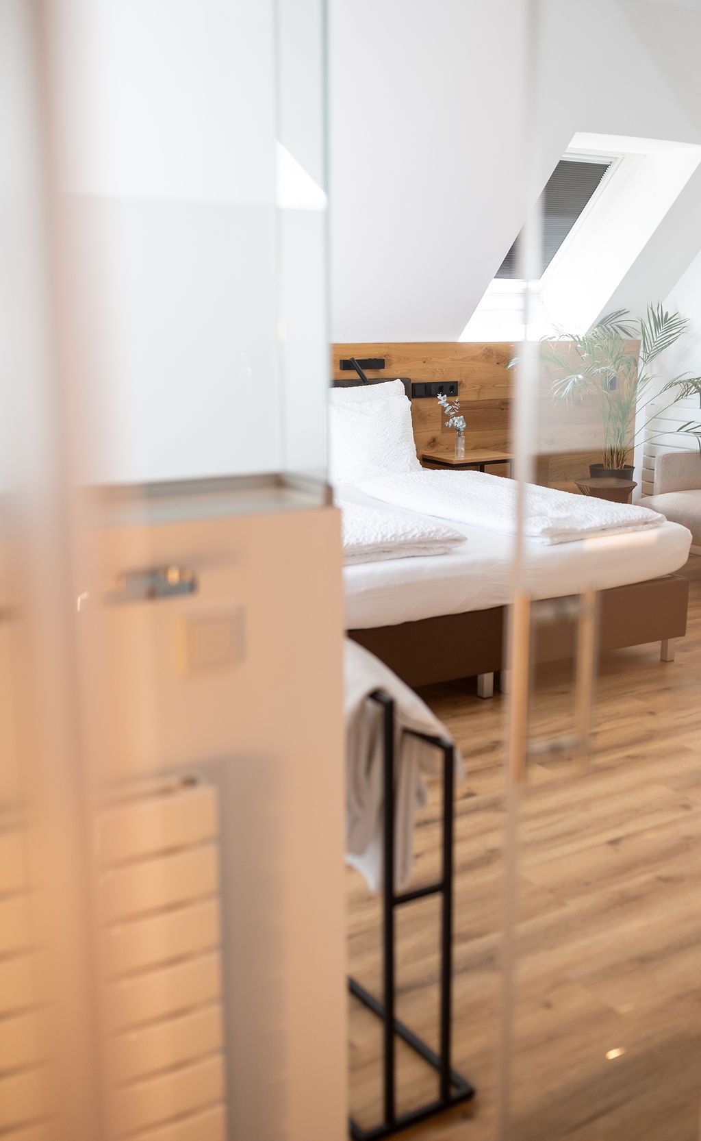Rooftop Suite mit großem Doppelbett. Freistehende Badewanne neben dem Bett und offenes Badezimmer.