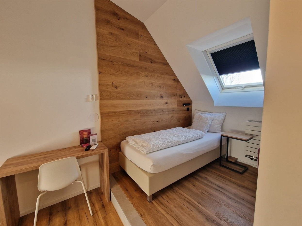 Roof top Einzelzimmer. Bett an holzverkleideten Wand. Warme Beleuchtung