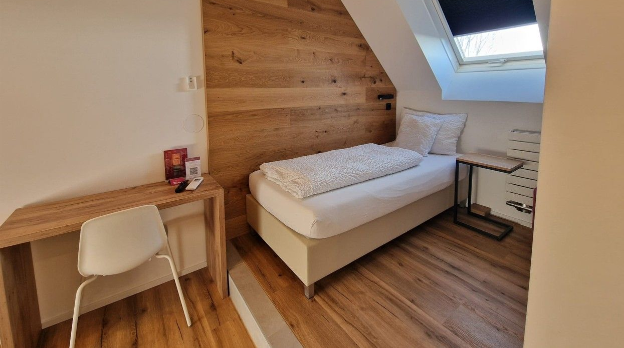 Roof top Einzelzimmer. Bett an holzverkleideten Wand. Warme Beleuchtung
